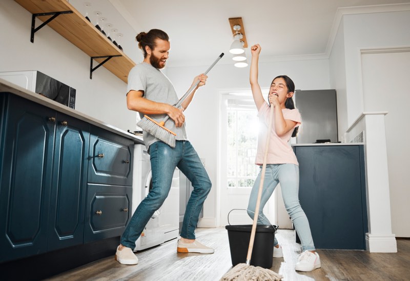 Having fun doing chores dancing and singing father and daughter cleaning the living room together at home Carefree happy and cheerful parent bonding doing housework and playing with little girl | WilkComm Reno